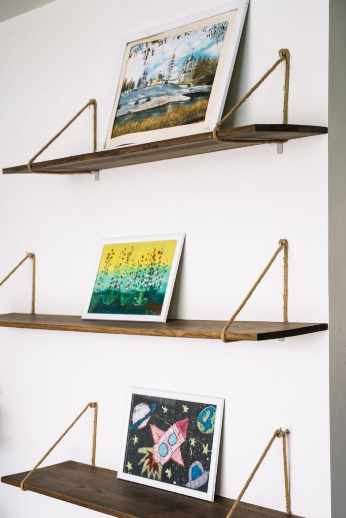 Three wall-mounted shelves with decorative pictures in a bedroom