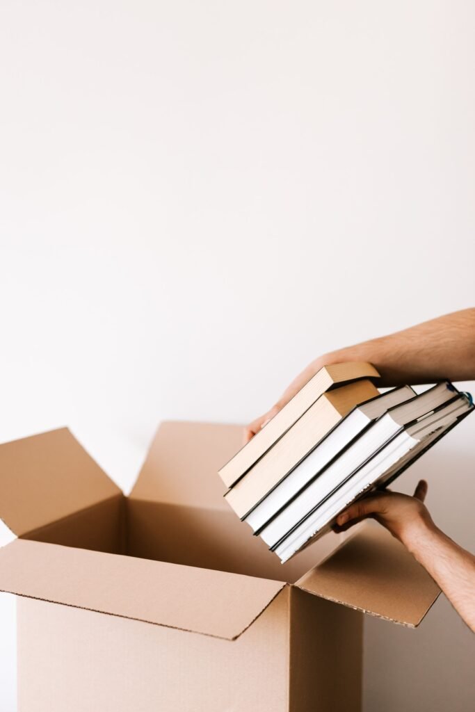 Person learning how to declutter your home by sorting books into boxes