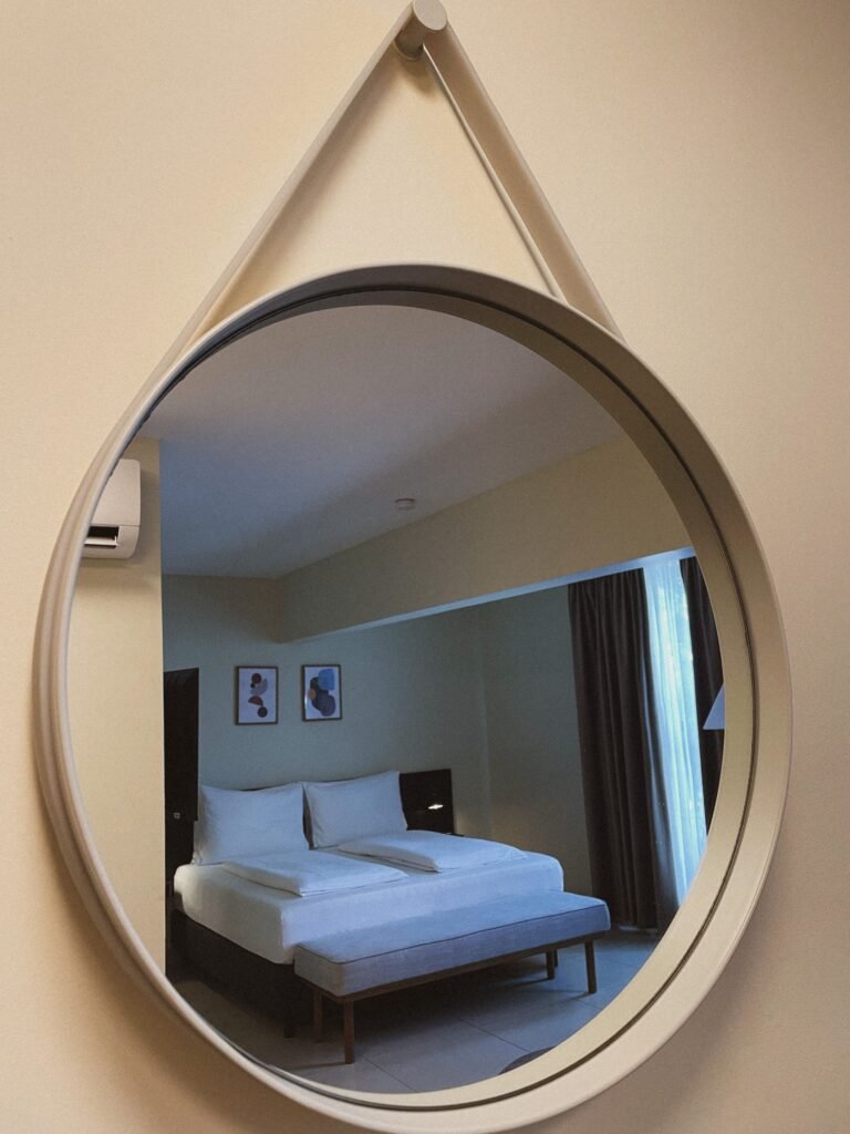 Wall-mounted mirror reflecting a bed in a bedroom