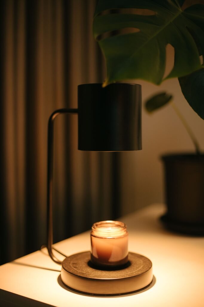 Candle warmer lamp with a lit candle in a cozy setting